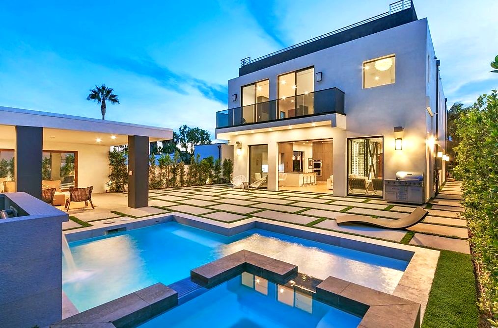 Home at dusk with lighting, outdoor entertainment and pool controlled by a smart home system